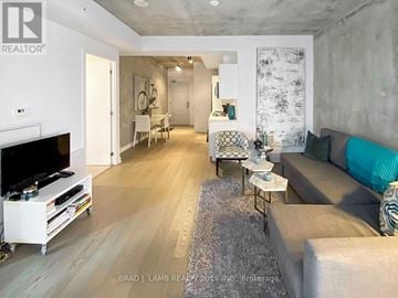 Toronto (Waterfront Communities) condo for rent - A living room with a grey couch and a white entertainment center.
