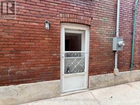 Toronto (Junction Area) apartment for rent - A white door with a glass window and a metal grill is on a red brick wall.