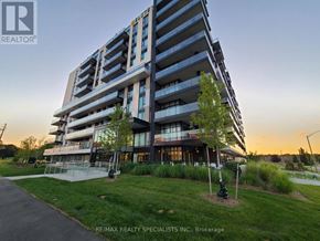 Brantford condo for rent - A modern multi-story building with a lawn in front and a clear sky in the background.
