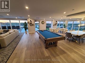 Brantford condo for rent - A billiard table is in the middle of a living room with a couch and chairs.