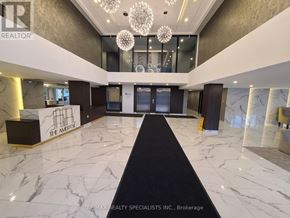 Brantford condo for rent - A spacious lobby with marble floors and a black carpet leading to a reception desk.