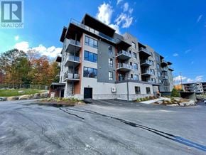 Huntsville (Chaffey) condo for rent - A large apartment building with a parking lot in front.