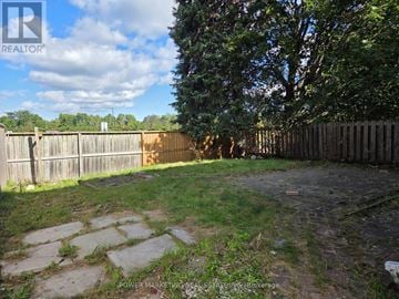 Ottawa apartment for rent - A backyard with a wooden fence and a tree.