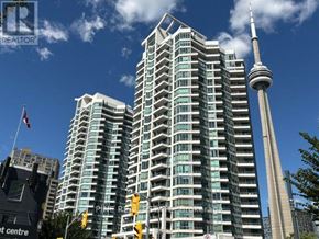 Toronto (Waterfront Communities) condo for rent - A tall building with a glass facade stands next to a tall tower with a spire.