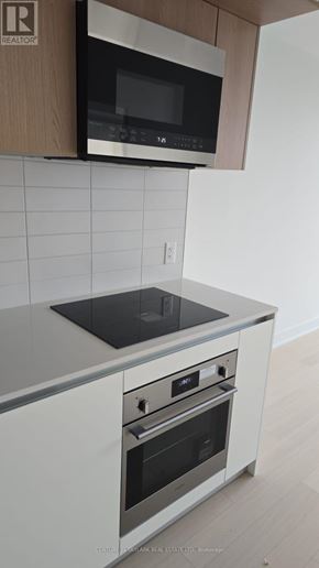 Toronto (Annex) condo for rent - A modern kitchen with a stove top oven and microwave above it.