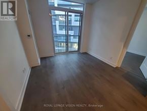 Toronto (Bayview Village) condo for rent - A room with wooden floors and a large window overlooking a cityscape.