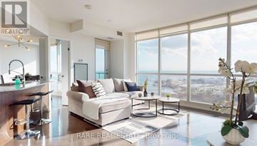 Toronto (Niagara) condo for rent - A well-lit, modern living room with a view of the cityscape outside the large windows.