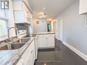 Toronto (Mimico) triplex for rent - A kitchen with white cabinets and a marble countertop.