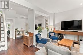 Toronto (South Riverdale) townhouse for rent - A living room with a staircase on the left side and a television on the right side.