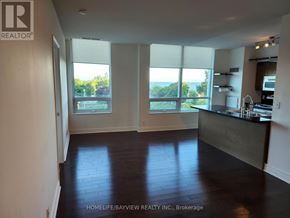 Toronto (South Parkdale) condo for rent - A spacious kitchen and living room with hardwood floors and large windows.