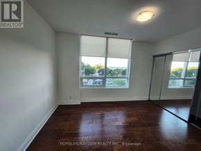 Toronto (South Parkdale) condo for rent - A room with a window showing a parking lot outside.