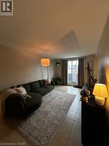New Hamburg apartment for rent - A living room with a black couch and a lamp on a table.