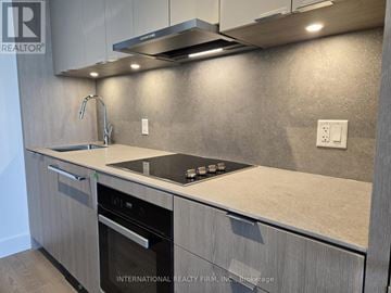 Toronto (Bayview Village) condo for rent - A modern kitchen with a stainless steel oven and a granite countertop.