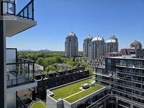 Toronto (Bayview Village) condo for rent - A view from a balcony of a building with a green lawn and several tall buildings in the background.