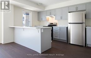 Clarington (Bowmanville) townhouse for rent - A kitchen with white appliances and cabinets.