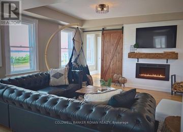 Barrie (Lakeshore) apartment for rent - A living room with a black leather couch and a fireplace.