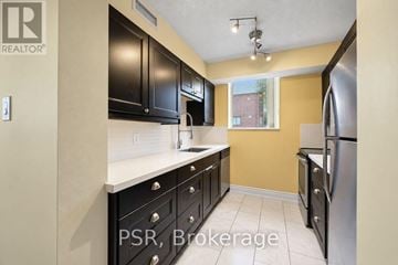 Oakville (Oo Old Oakville) condo for rent - A kitchen with black cabinets and a stainless steel refrigerator.