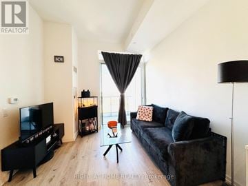 Vaughan (Vaughan Corporate Centre) condo for rent - A black couch with a red pillow is in the middle of a living room.