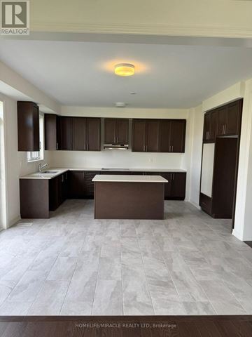 Adjala-Tosorontio (Colgan) apartment for rent - A spacious kitchen with brown cabinets and a central island.
