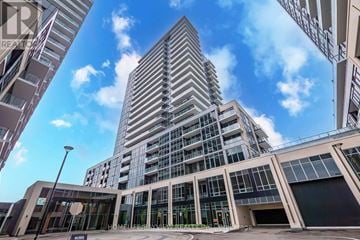 Milton (Tm Timberlea) condo for rent - A modern building with a glass facade stands tall against a partly cloudy sky.
