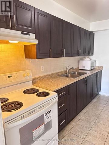 Toronto (Crescent Town) condo for rent - A kitchen with a white stove and black cabinets.