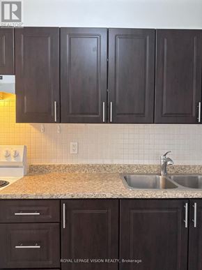 Toronto (Crescent Town) condo for rent - A kitchen with brown cabinets and a sink.