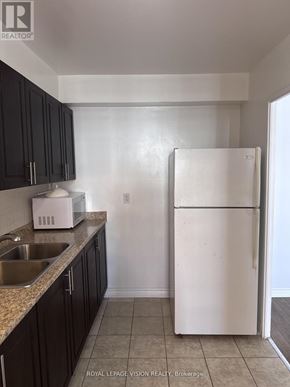Toronto (Crescent Town) condo for rent - A white refrigerator in a kitchen with black cabinets.