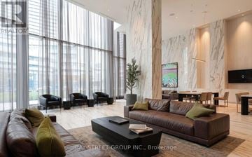 Mississauga (City Centre) condo for rent - A living room with a brown couch and a coffee table in front of a large window.