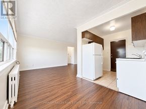 Toronto (Briar Hill-Belgravia) multi-family for rent - A spacious room with wood flooring and a white refrigerator.