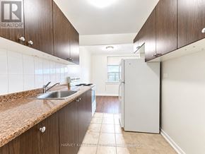 Toronto (Briar Hill-Belgravia) multi-family for rent - A kitchen with brown cabinets and a white refrigerator.