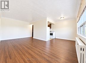 Toronto (Briar Hill-Belgravia) multi-family for rent - A spacious room with wood flooring and a white kitchenette.