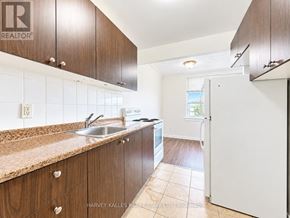 Toronto (Briar Hill-Belgravia) multi-family for rent - A kitchen with brown cabinets and a sink.