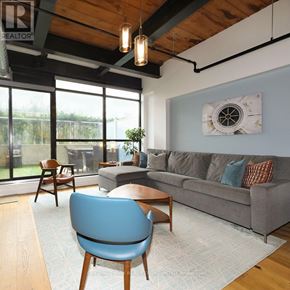 Toronto (Niagara) condo for rent - A living room with a grey couch, a blue chair and a wooden table.