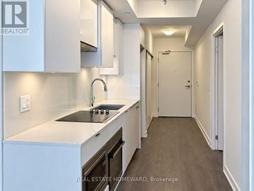 Toronto (Mount Pleasant West) condo for rent - A modern kitchen with white cabinets and a dark countertop.