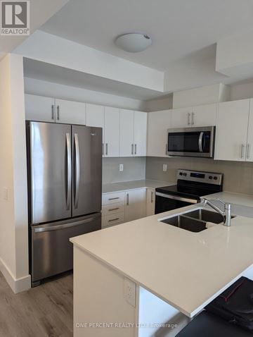 Collingwood condo for rent - A modern kitchen with a stainless steel refrigerator and white countertops.