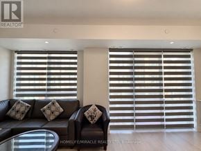 Brampton (Bram East) townhouse for rent - A living room with a black leather couch and a glass coffee table.