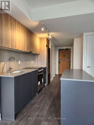 Toronto (Clanton Park) condo for rent - A kitchen with wooden cabinets and a grey counter.