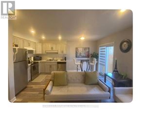 Niagara Falls (Oldfield) townhouse for rent - A well-lit kitchen and living room with a refrigerator, stove, and couch.