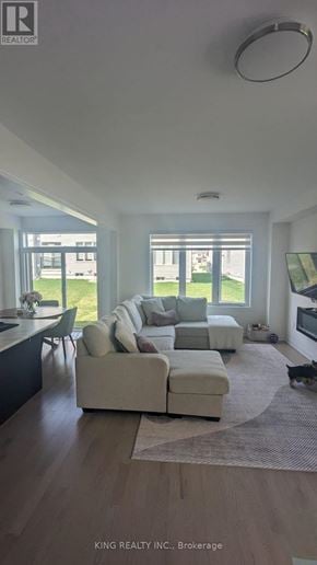 Shelburne townhouse for rent - A modern living room with a large sectional sofa and a kitchen area in the background.