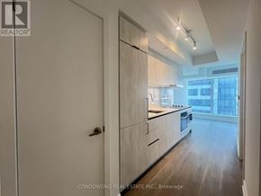 Toronto (Bay Street Corridor) condo for rent - A modern kitchen with white cabinets and a wooden floor.