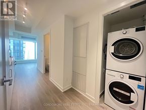 Toronto (Bay Street Corridor) condo for rent - A white washer and dryer are in a small laundry room.