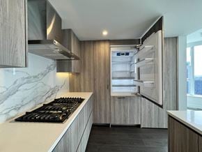 Surrey apartment for rent - A modern kitchen with a marble countertop and a stainless steel refrigerator.