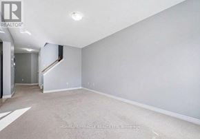 Guelph (Grange Road) apartment for rent - A spacious room with a carpeted floor and a staircase leading to another room.