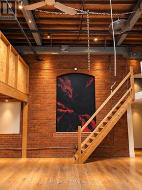 Toronto (Dufferin Grove) condo for rent - A staircase with a wooden handrail and steps leads up to a window with a red and black design.