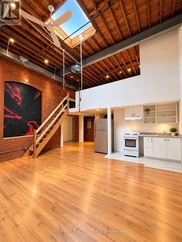 Toronto (Dufferin Grove) condo for rent - A spacious open plan living and kitchen area with wooden floors and a skylight.