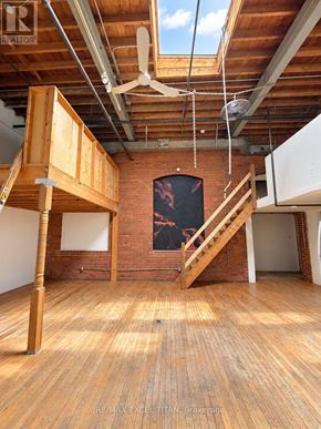 Toronto (Dufferin Grove) condo for rent - A room with wooden floors and a brick wall with a staircase.