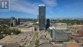 Kitchener condo for rent - A cityscape with a tall building in the center and a parking lot in the foreground.