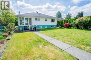 Vancouver apartment for rent - A house with a blue trim and a grey roof is surrounded by a green lawn and a sidewalk.
