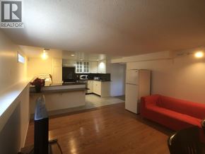 Vancouver apartment for rent - A living room with a red couch and a kitchen area in the background.