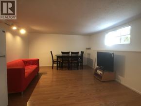 Vancouver apartment for rent - A living room with a red couch, a black dining table and chairs, and a television.